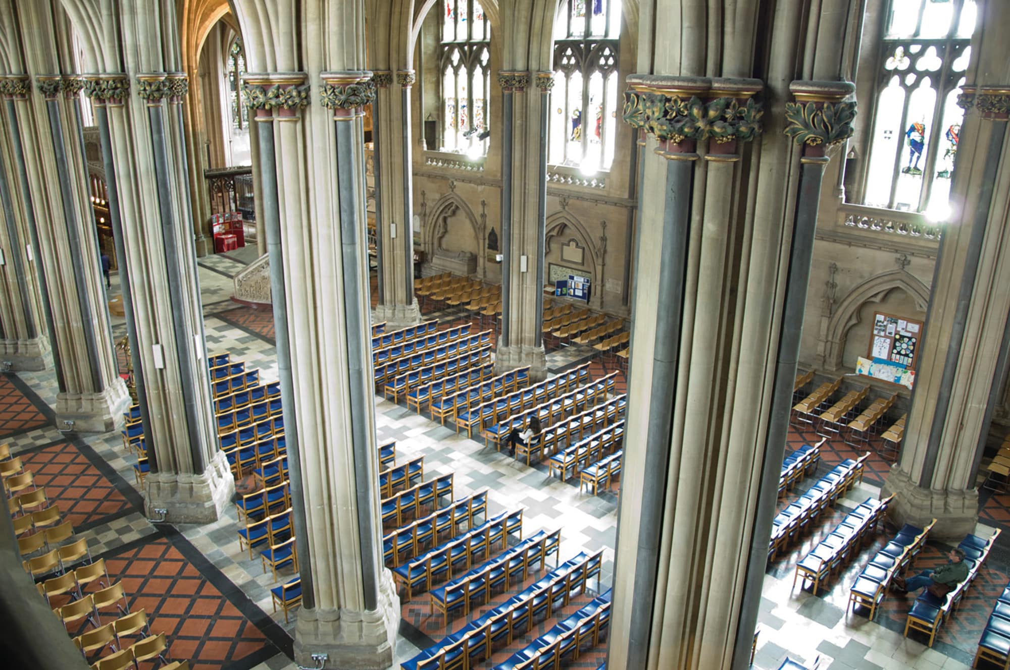 Rows of blue seats in the nave of Bristol Cathedral are seen between decorative pillars